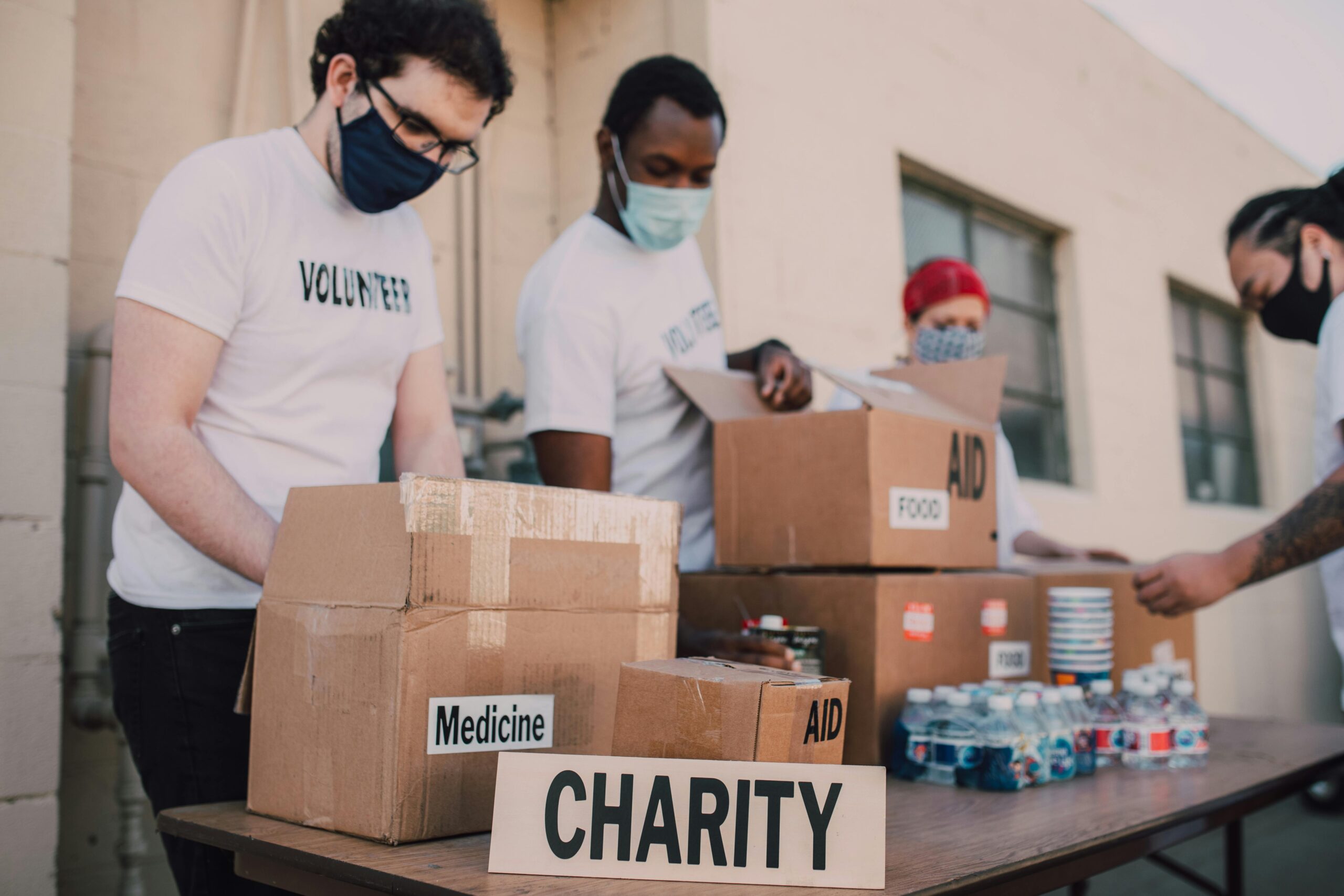 Volunteers organizing aid boxes labeled medicine, food, and water for charity, symbolizing collective efforts to support communities and promote environmental sustainability through charitable donations